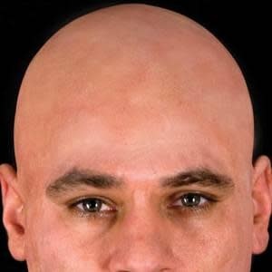 A man wearing a bald cap matching his skin tone.