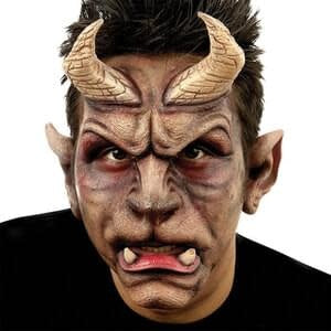 A man wearing prosthetic makeup kit that turns him into a beast like character giving him horns, beast like ears, and two big bottom teeth. 