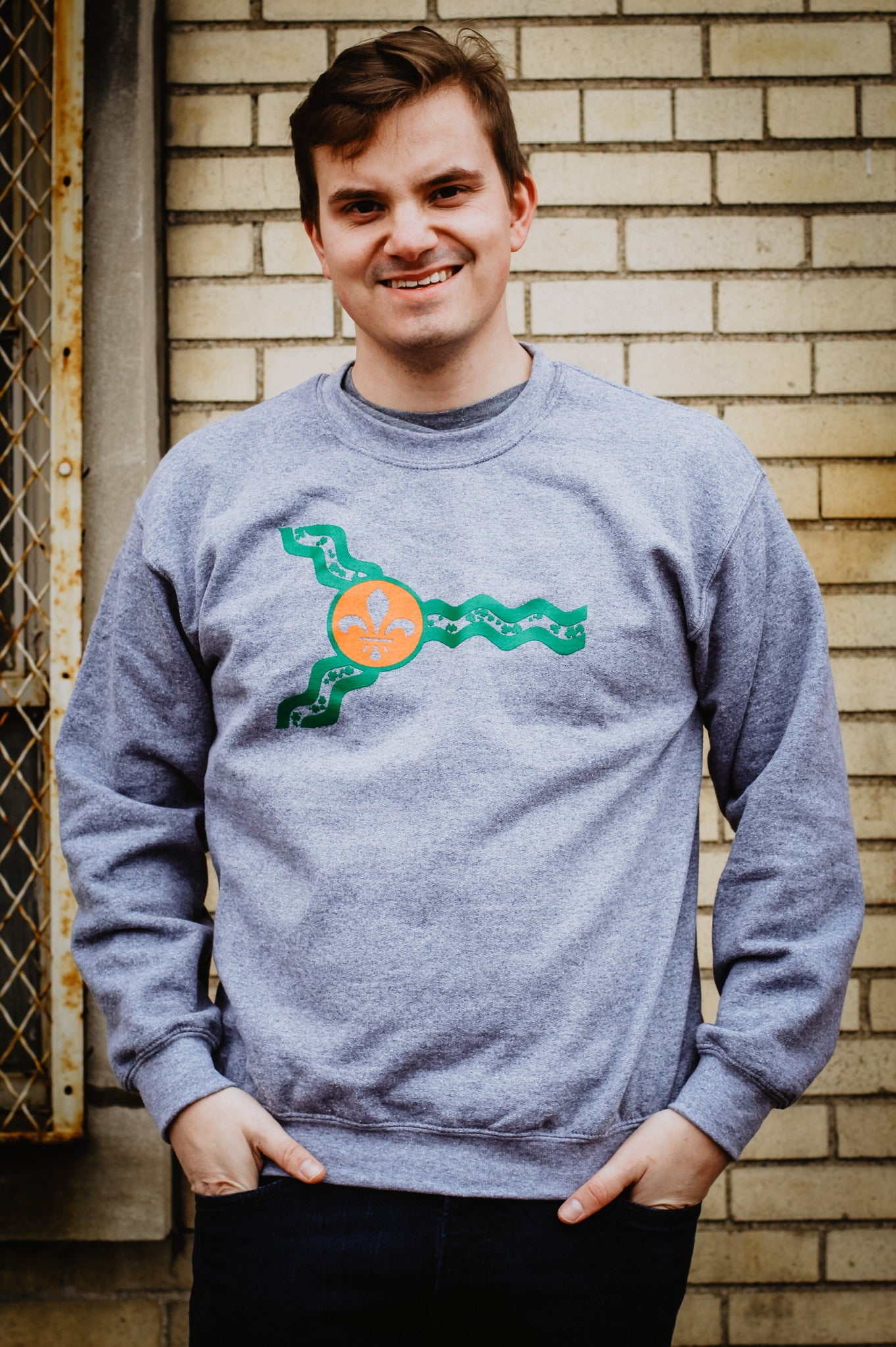 A man wearing a grey St. Louis flag St. Patrick's Day crewneck sweatshirt.
